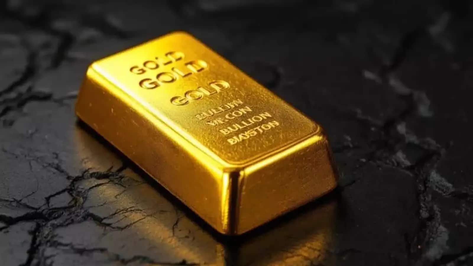 یک شمش طلا روی سطح سنگی سیاه رنگ